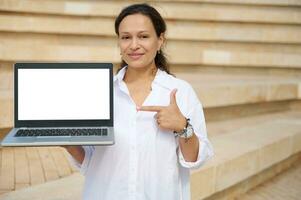jovem mulher dentro branco camisa, apontando índice dedo às branco brincar digital tela com cópia de espaço, sorridente às Câmera foto