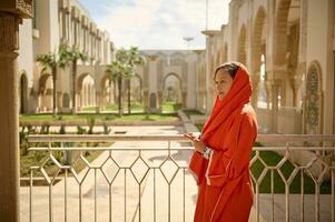 lindo meio Oriental muçulmano mulher com cabeça coberto dentro hijab, em pé com em forma de xícara mãos às Hassan ii mesquita foto