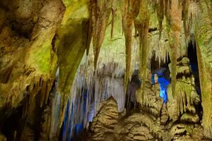 carste caverna, surpreendente Visão do estalactites e estalagnites dentro colorida brilhante luz, lindo natural ponto de referência dentro Turística lugar. foto