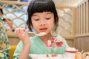 fofa pequeno ásia criança menina comendo Comida foto