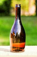 uma Castanho vidro garrafa sentado em uma de madeira mesa foto
