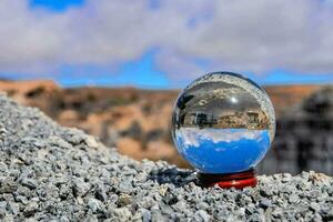 uma vidro bola sentado em topo do uma Rocha foto