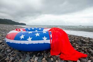 uma bóia salva-vidas com a americano bandeira pintado em a Beira Mar. período de férias período de férias em americano praias. foto