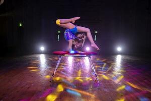 uma pequeno menina circo artista com uma flexível corpo executa em estágio. a criança do a equilibrista. foto
