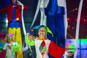 pequeno menina é dançando dentro uma palhaço fantasia. a criança executa em estágio. foto