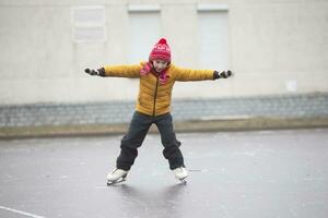 pequeno Garoto dentro inverno roupas aprende para skate.a criança em a gelo pista. foto