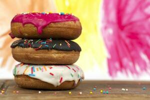 criativo doce Comida. uma pilha do envidraçado colorida sortido rosquinhas em uma brilhante aguarela pintado fundo. foto