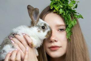 adolescente menina com uma grupo do salsinha e uma Coelho. foto