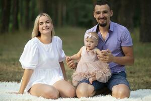 marido, esposa e seus pequeno filha para uma andar dentro a parque. retrato do uma jovem família com uma criança pequena dentro a floresta. foto