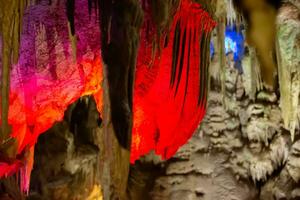 carste caverna, surpreendente Visão do estalactites e estalagnites dentro colorida brilhante luz, lindo natural ponto de referência dentro Turística lugar. foto