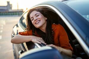cortada tiro do a atraente jovem mulher inclinado Fora do uma carro janela em uma estrada viagem foto