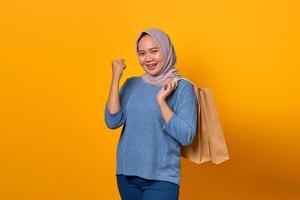 mulher asiática sorridente segurando uma sacola de compras e comemorando a sorte foto