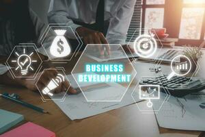 o negócio desenvolvimento conceito, o negócio equipe analisando renda gráficos e gráficos em escritório escrivaninha com o negócio desenvolvimento ícone em virtual tela. foto
