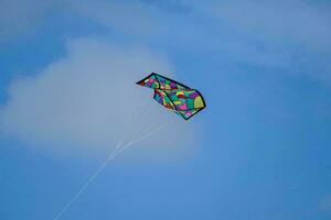 uma colorida pipa vôo dentro a azul céu foto