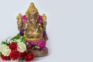 uma ganesh estátua fez do argila é Além disso uma rosa flor em branco fundo. foto