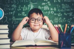 menino pensativo com livro na sala de aula foto