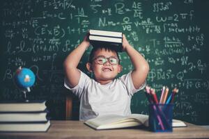 menino com livros sentado na sala de aula foto