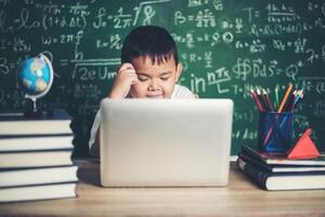 criança usa laptop de computador em sala de aula. foto