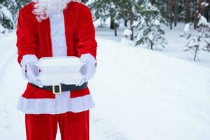 recipientes de serviço de entrega de comida nas mãos do papai noel ao ar livre na neve. promoção de véspera de natal. pedido quente pronto, caixa plástica descartável. catering de férias de ano novo. copie o espaço, simular foto