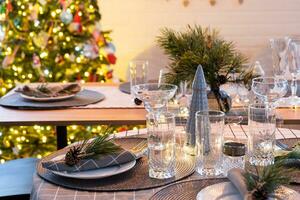 servindo uma festivo mesa com pratos, garfos, facas, guardanapos, óculos fechar-se dentro a moderno interior do uma loft casa decorado para Natal e Novo ano. esperando para convidados para uma festivo jantar foto