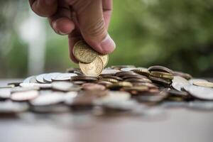 economizando o conceito de dinheiro. mão colocando dinheiro pilha de moedas foto