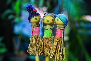três crianças brinquedo bonecas fez do madeira e Palha em uma borrado fundo foto