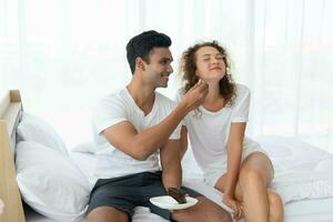 sorridente e feliz casal tendo sobremesa dentro cama dentro a manhã foto