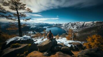 mulher sentado em topo do uma montanha e olhando às a lago. foto