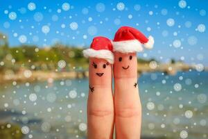 dedo arte do feliz casal dentro Natal chapéus em repouso em a mar foto