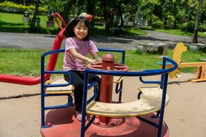 alegre criança menina jogando em Parque infantil dentro a parque. saudável verão atividade para crianças. foto