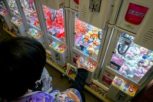 Osaka cidade, jp, 2019 - imagem do Alto ângulo Visão uma Garoto apreciar e jogando bonecas gabinete pega máquina. bonecas gabinete pega é uma operado por moedas entretenimento máquina popular dentro Japão e Ásia foto