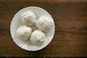 topo Visão chinês quente pão em branco cerâmico prato e de madeira mesa fundo. chinês quente pão ou salabão estão vários tipos popular dentro inverno dentro China, hong kong, Taiwan. foto