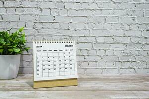branco marcha 2024 calendário em escritório de madeira escrivaninha com em vaso plantar. foto