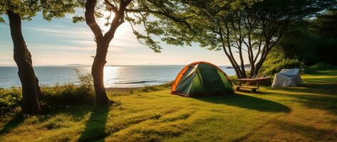 acampamento barraca e acampamento equipamento em verde Relva com mar Visão fundo ai gerado foto