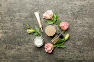 composição com Cosmético produtos e lindo rosas em cimento fundo. plano deitar foto