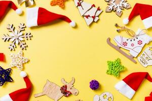 vista superior das decorações de natal e chapéus de papai noel em fundo amarelo. conceito de feliz feriado com espaço de cópia foto