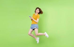 jovem asiática pulando sobre um fundo verde