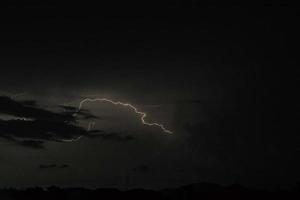 raio ataca na noite escura com a nuvem de chuva foto