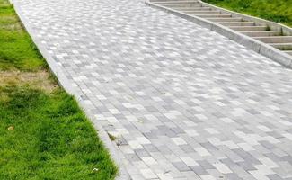 uma longa descida coberta com lajes de pavimentação cinza. a rampa é pavimentada com foto