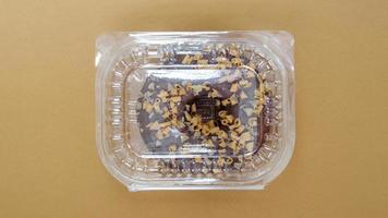rosquinha de chocolate em um recipiente de plástico em um fundo marrom ou café foto