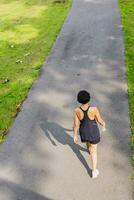 traseiro Visão mulher exercício caminhando dentro a parque. foto