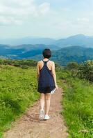 mulher exercício caminhando em encosta trilha com montanha visualizar. foto