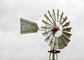 uma moinho de vento com uma metal pólo e uma vermelho bandeira foto