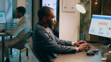 boneca Fora tiro do com experiência companhia pessoal sentado às mesas dentro escritório, imputando dados em computadores durante a noite. especializado funcionários membros dentro moderno relaxado local de trabalho resolução tarefas durante turno da noite foto