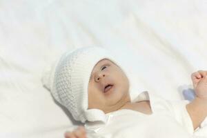 recém-nascido bebê Garoto dentro tricotar chapéu pacificamente deitado em branco foto