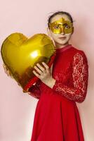 mulher vestindo mascarada mascarar e segurando coração em forma ar balão. dia dos namorados dia, aniversário, aniversário, festivo, bola celebração conceitos foto