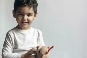 5 anos adorável pequeno criança Garoto jogando com pelúcia Urso brinquedo foto