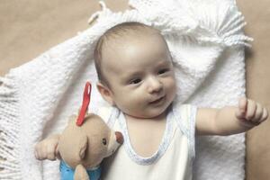 2 mês bebê Garoto mentindo. fechar-se do adorável fofa recém-nascido bebê Garoto do dois meses em suave têxtil. adorável criança jogando com pelúcia brinquedo foto