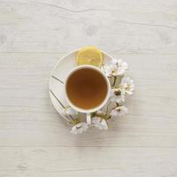 xícara de chá de limão com flores e limão