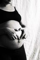 grávida mulher às 9º mês mostrando coração com mãos foto